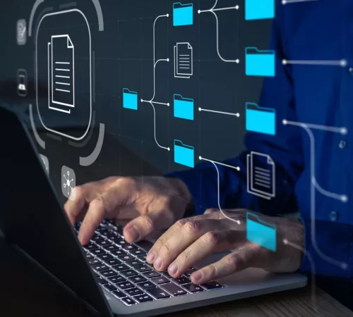 Document Management System (DMS) being setup by IT consultant working on laptop computer in office. Software for archiving, searching and managing corporate files and information. Business processes